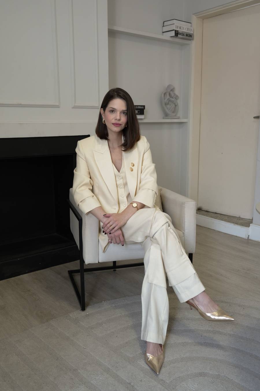 Gaby Linhares sentada em poltrona, de terninho off-white